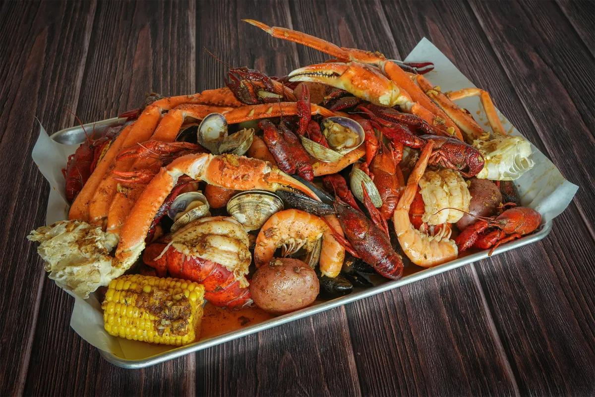Tray of snow crab legs, crawfish, shrimp, clams, corn and potatoes