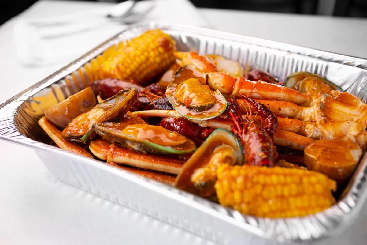 Catering tray of snow crab, mussels, shrimp and corn in Cajun sauce